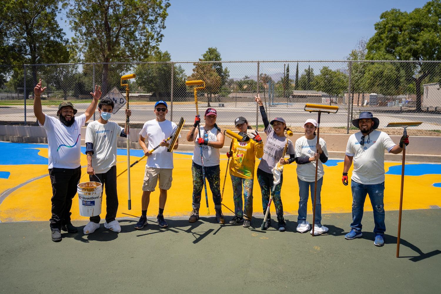 Volunteers paint a mural on a street using cool pavement coating.
